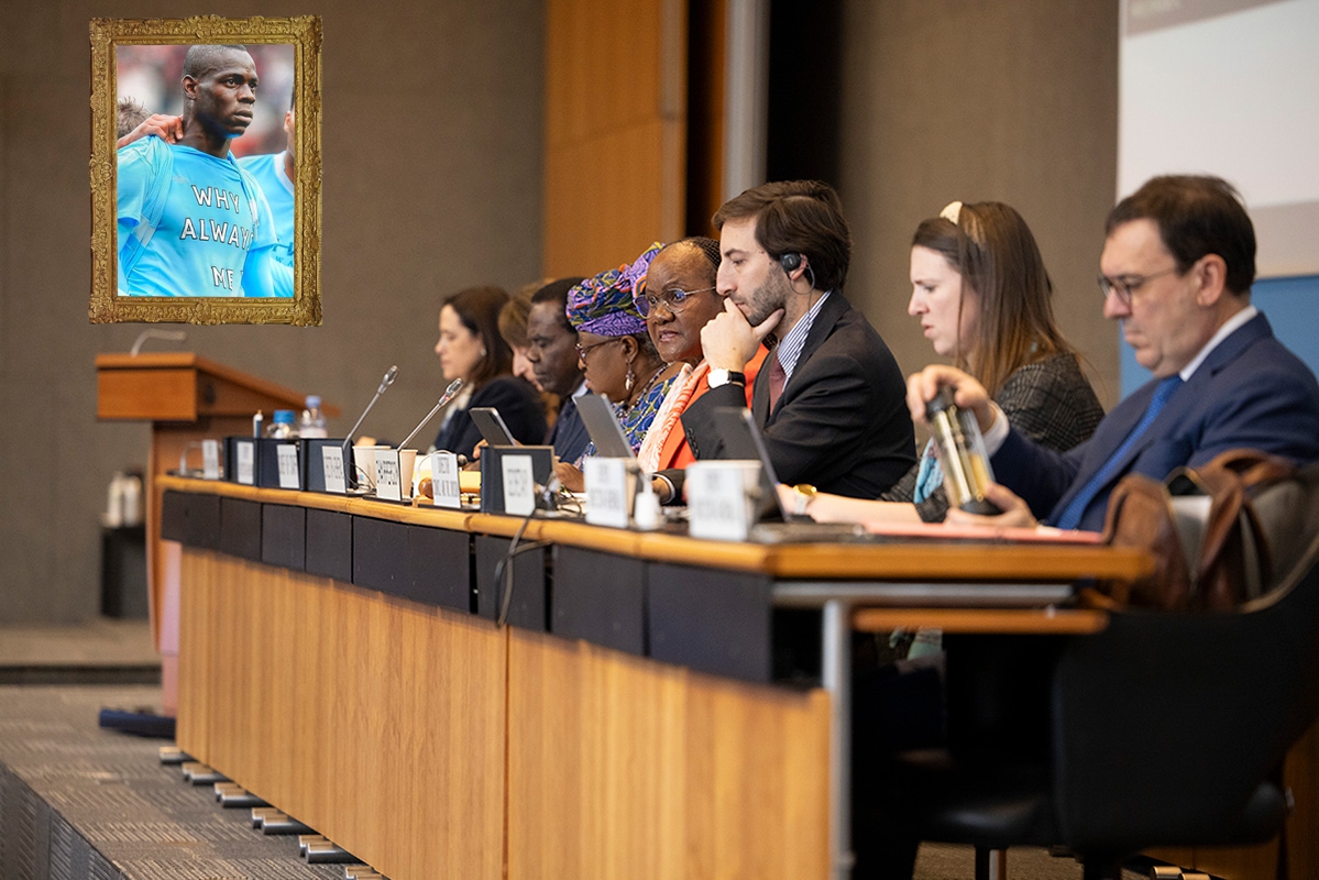 Photo of people on the podium during the WTO General Council meeting December 13-15, 2023, with a framed photo of Mario Balotelli wearing a shirt saying "why always me?" added on a wall.