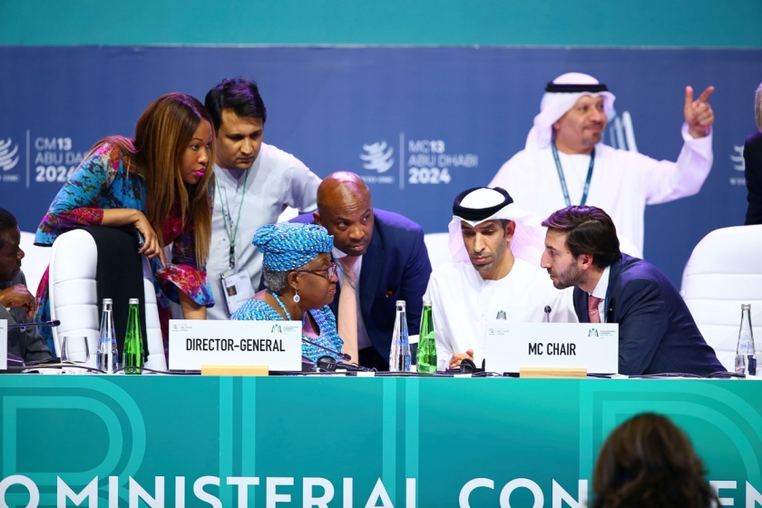 WTO Ministerial Conference, Abu Dhabi. officials huddle around the director-general and conference char on the podium